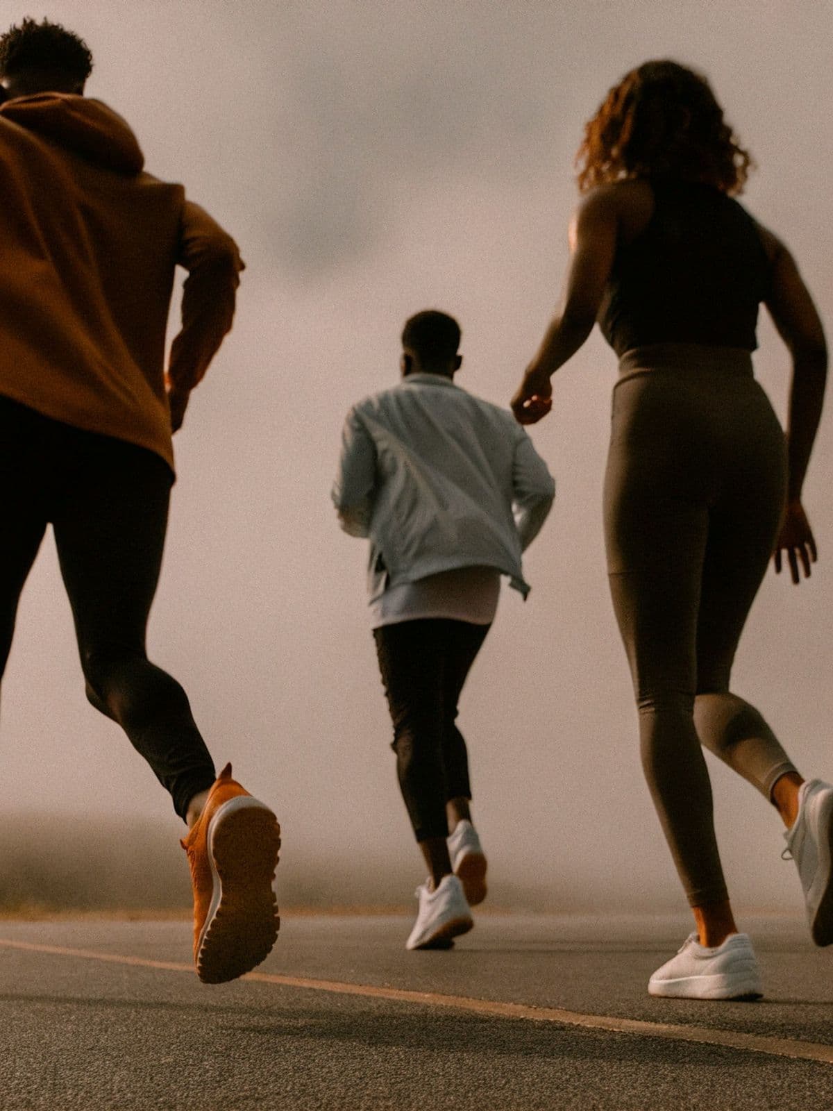 Three friends running together on an open road